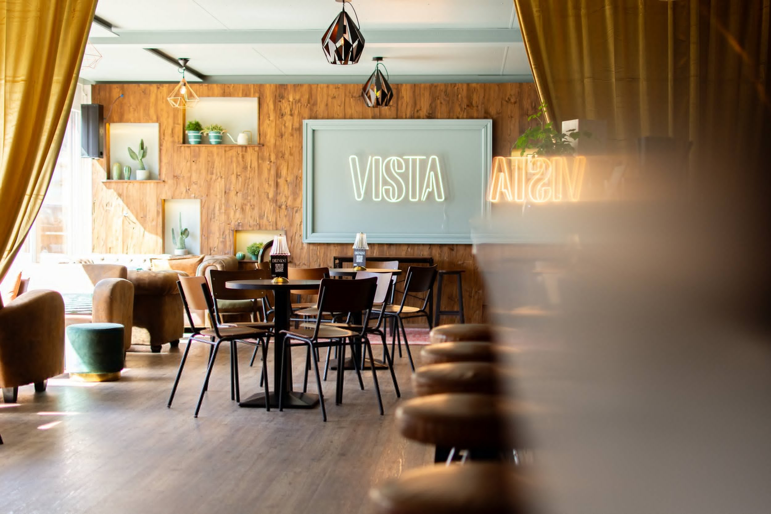 Weiter Blick durch den Innenraum der Vista Bar mit mehreren Tischen, Barhockern und Platz für eine grössere Gruppe.