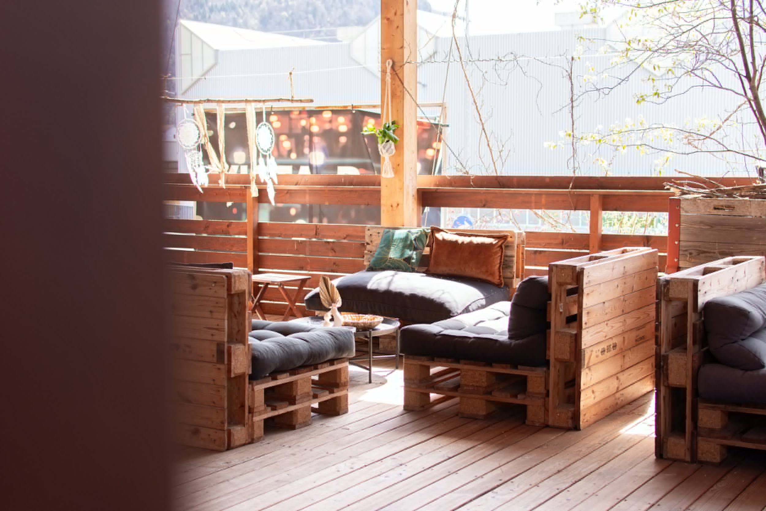 Lounge-Sitzbereich auf der Dachterrasse der Vista Bar mit Holzbänken, Kissen und Platz für eine grössere Runde.